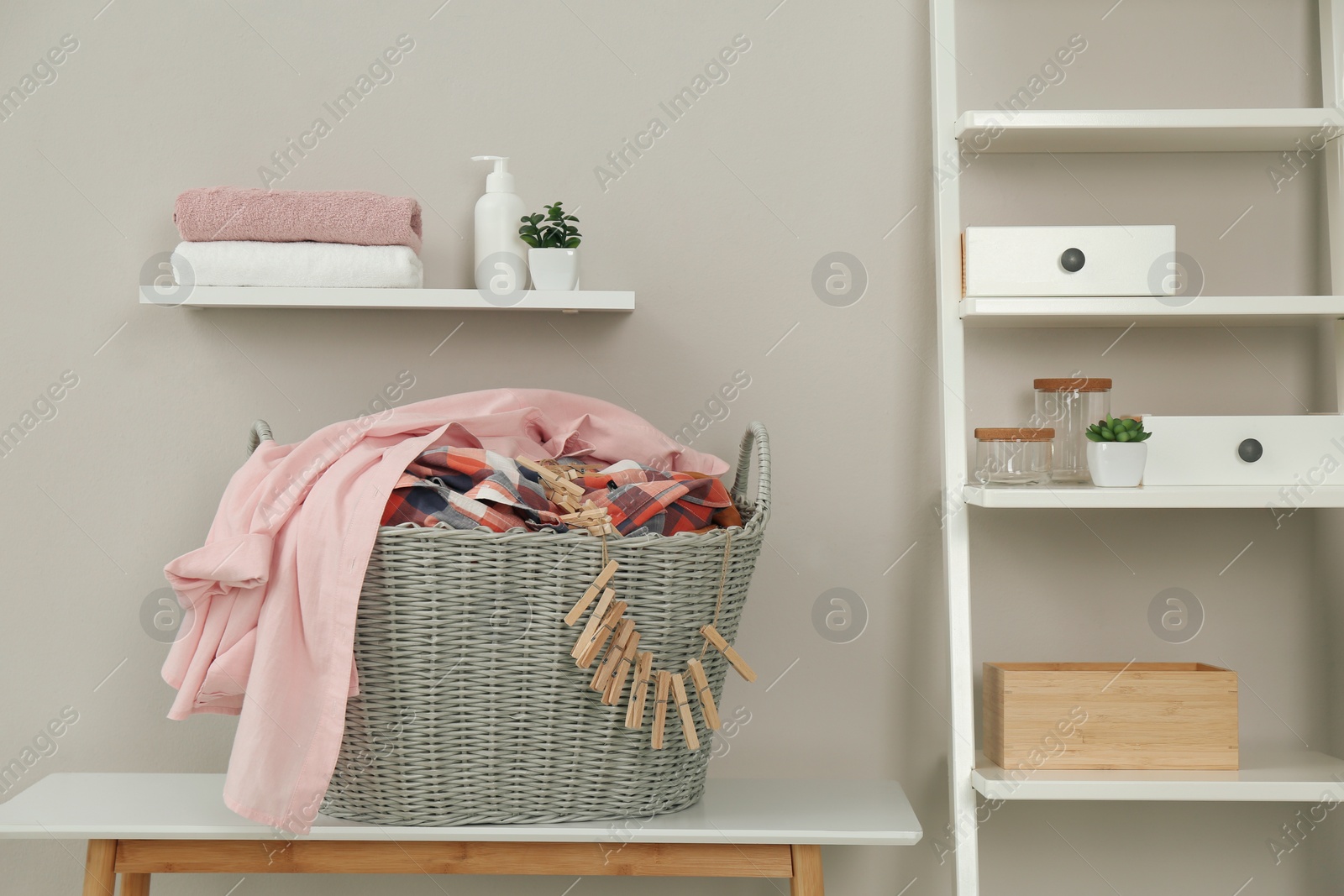 Photo of Wicker basket with dirty laundry and clothespins on table indoors