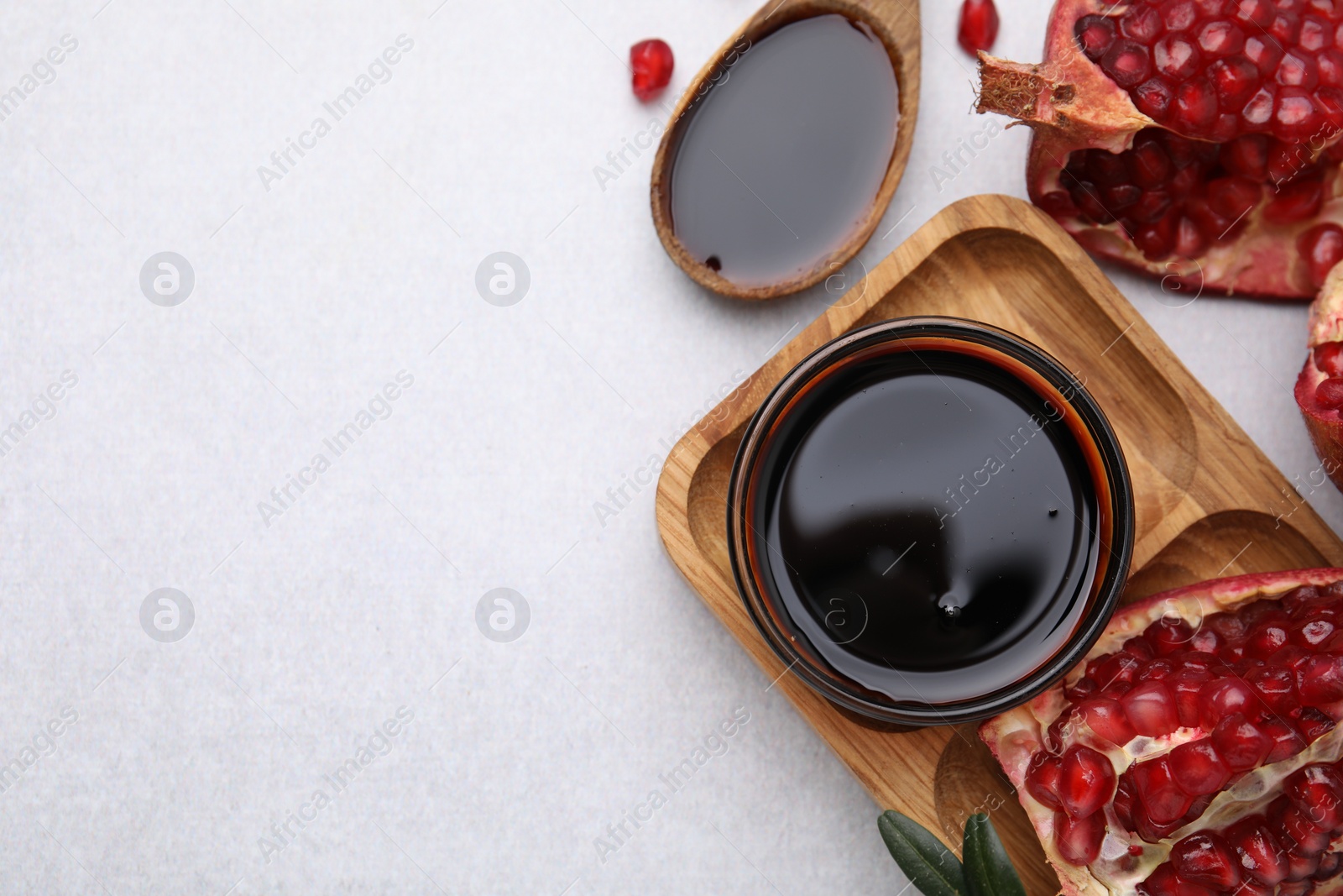 Photo of Tasty pomegranate sauce and fruits on light table, flat lay. Space for text