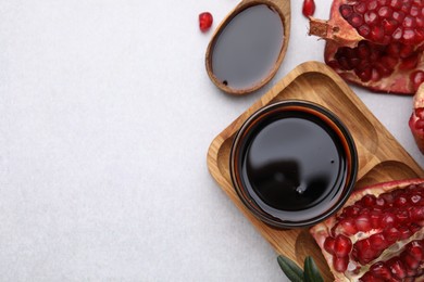 Tasty pomegranate sauce and fruits on light table, flat lay. Space for text