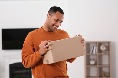 Photo of Happy young man with parcel at home. Internet shopping