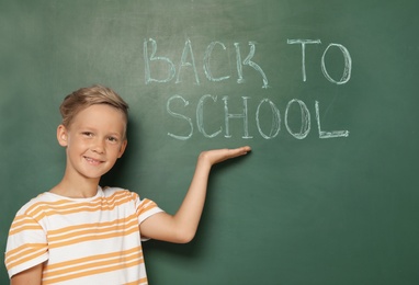 Photo of Little child near chalkboard with text BACK TO SCHOOL