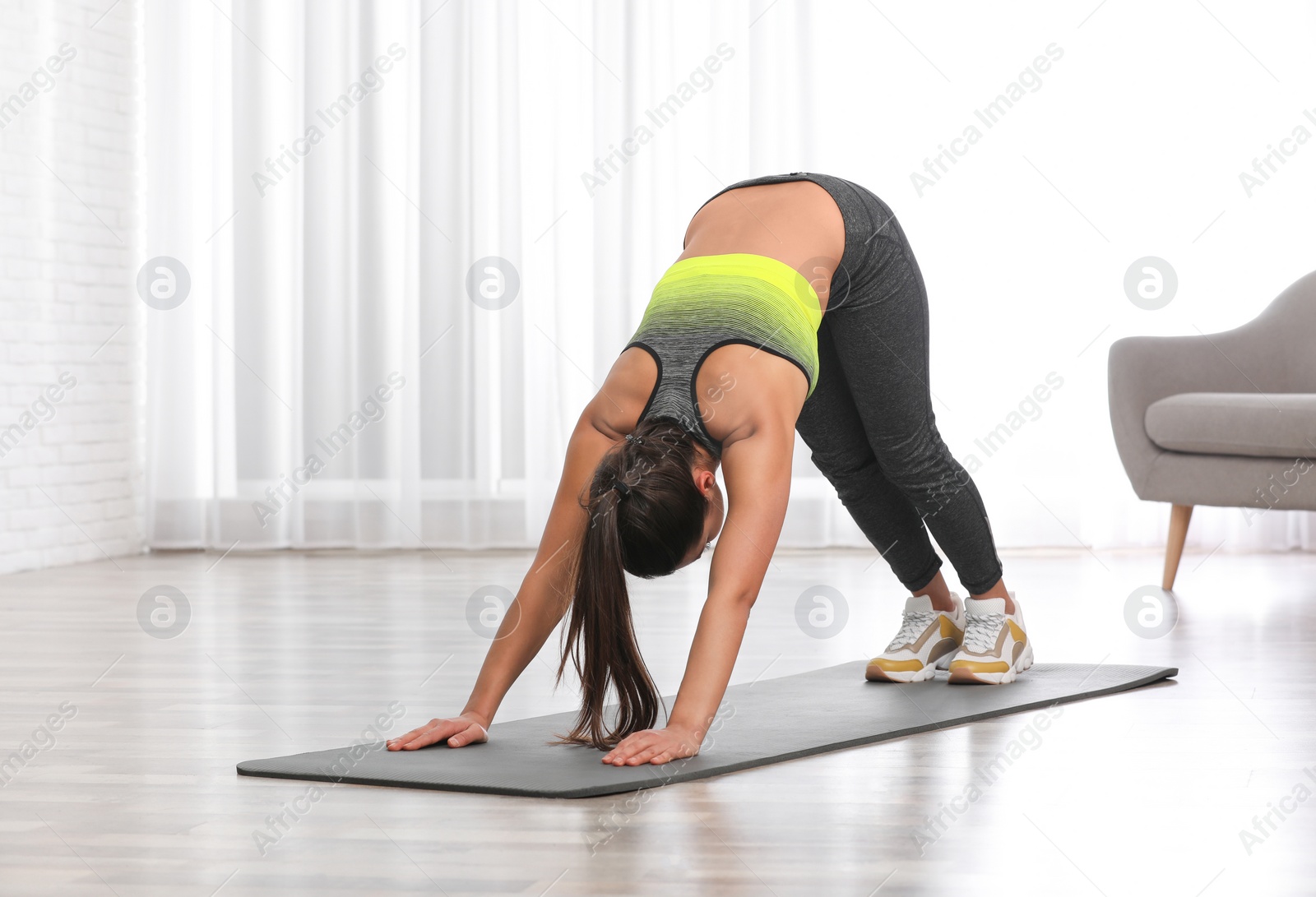 Photo of Young woman in fitness clothes doing exercise at home. Space for text