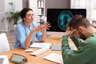 Photo of Neurologist consulting patient at table in clinic