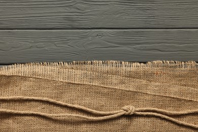 Photo of Burlap fabric and jute on grey wooden table, top view. Space for text