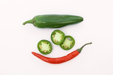 Photo of Whole and cut hot chili peppers on white background, flat lay