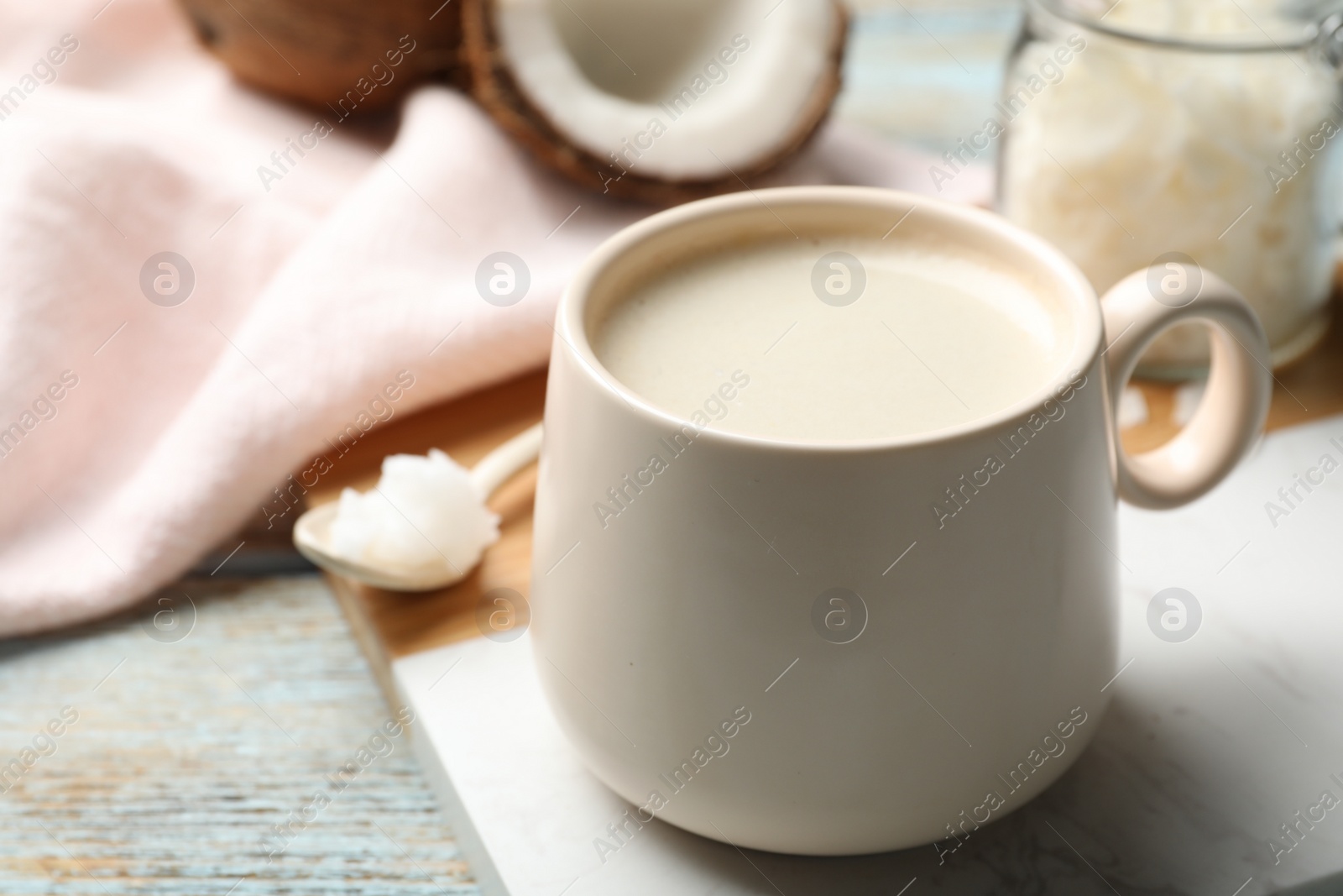 Photo of Delicious coffee with organic coconut oil on white wooden table