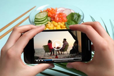 Image of Woman watching video on mobile phone at table during lunch, closeup