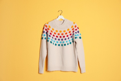 Hanger with stylish sweater on color background