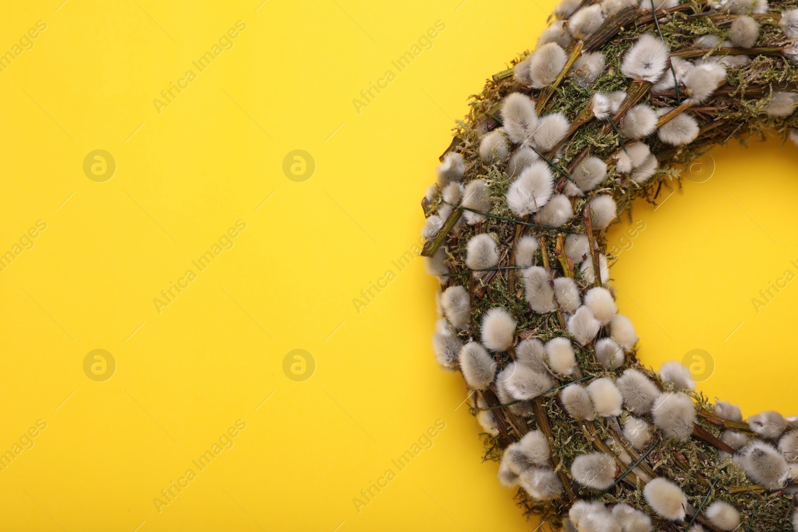 Photo of Wreath made of beautiful willow flowers on yellow background, top view. Space for text