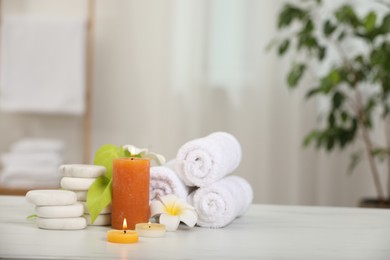 Composition with different spa products and plumeria flowers on white marble table indoors, space for text