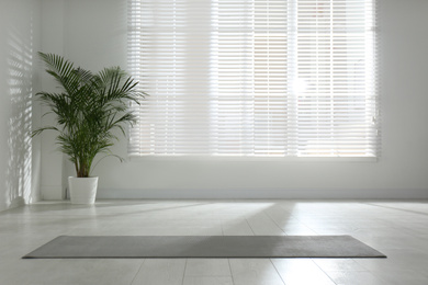 Photo of Unrolled grey yoga mat on floor in room. Space for text