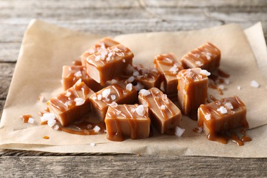 Photo of Yummy candies with caramel sauce and sea salt on wooden table