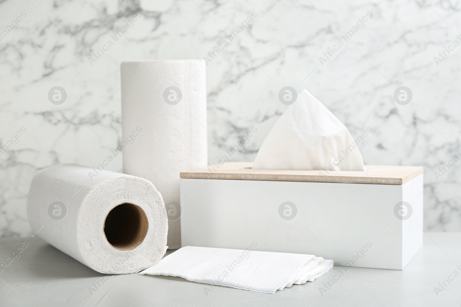 Photo of Clean napkins, box with tissues and rolls of paper towels on light table