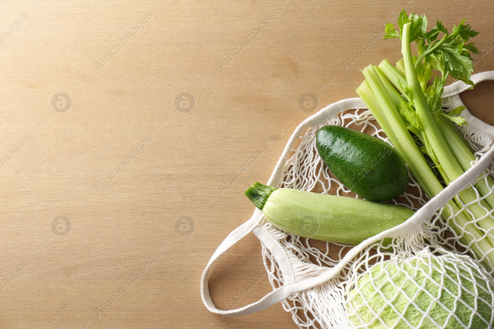 Photo of Different fresh vegetables in eco mesh bag on wooden table, top view