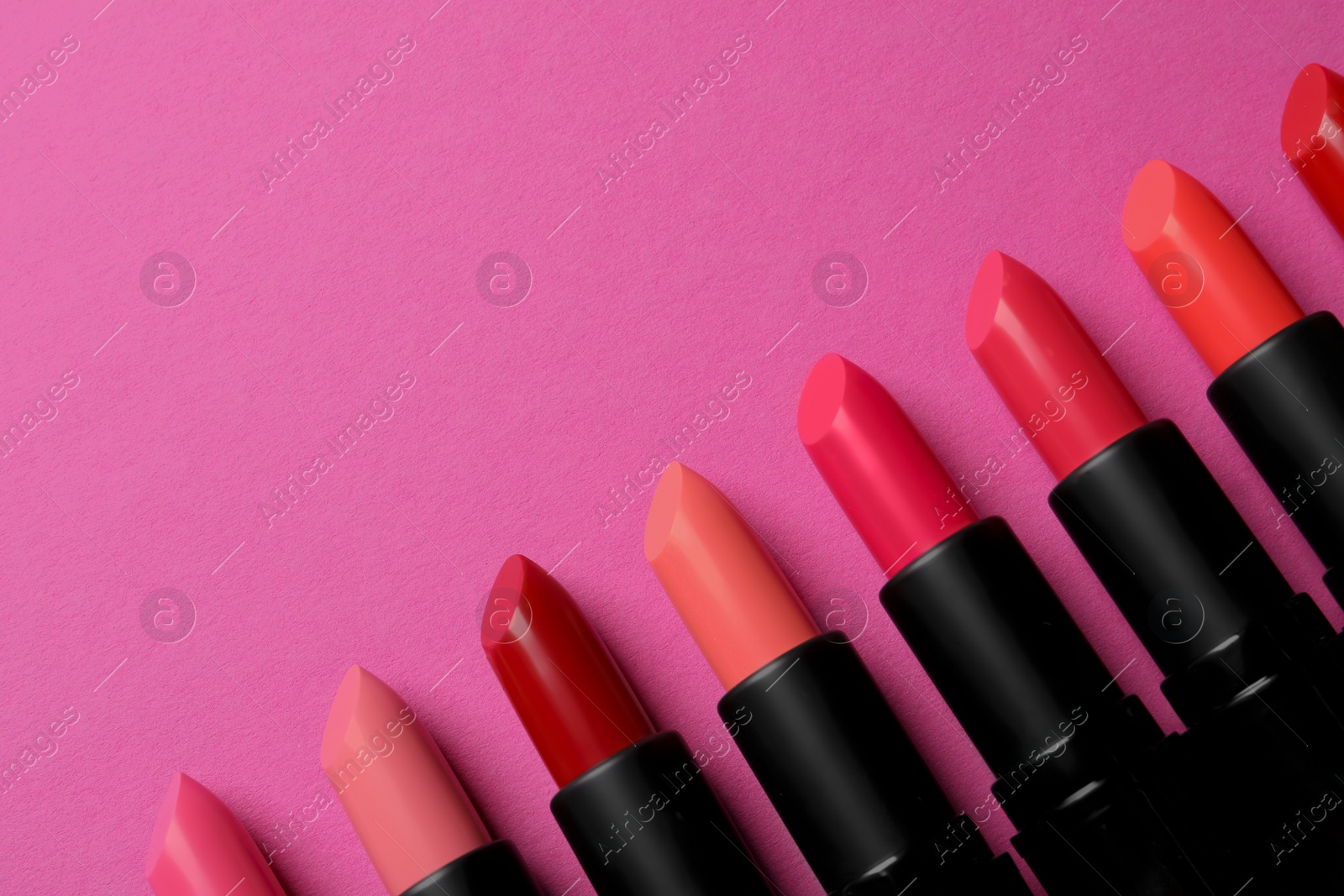 Photo of Beautiful lipsticks on pink background, flat lay. Space for text