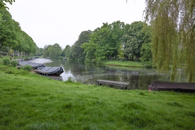 Photo of Picturesque view of green park with boats near river outdoors