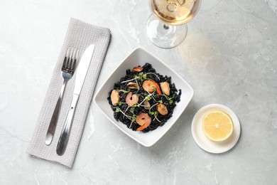 Delicious black risotto with seafood served on light grey marble table