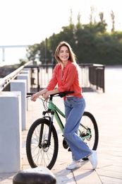 Young woman with bicycle in city on sunny day