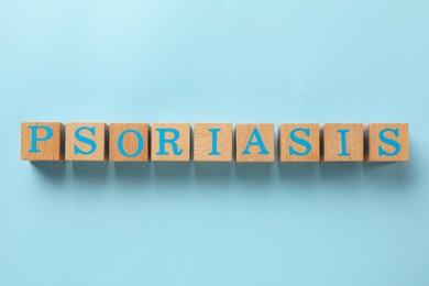 Word Psoriasis made of wooden cubes with letters on light blue background, top view