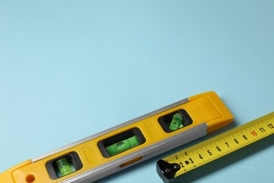 Photo of Building level and tape measure on light blue background