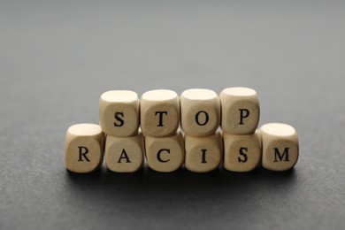 Photo of Phrase Stop Racism made of wooden cubes on grey table