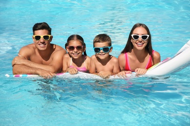 Photo of Happy family on inflatable mattress in swimming pool