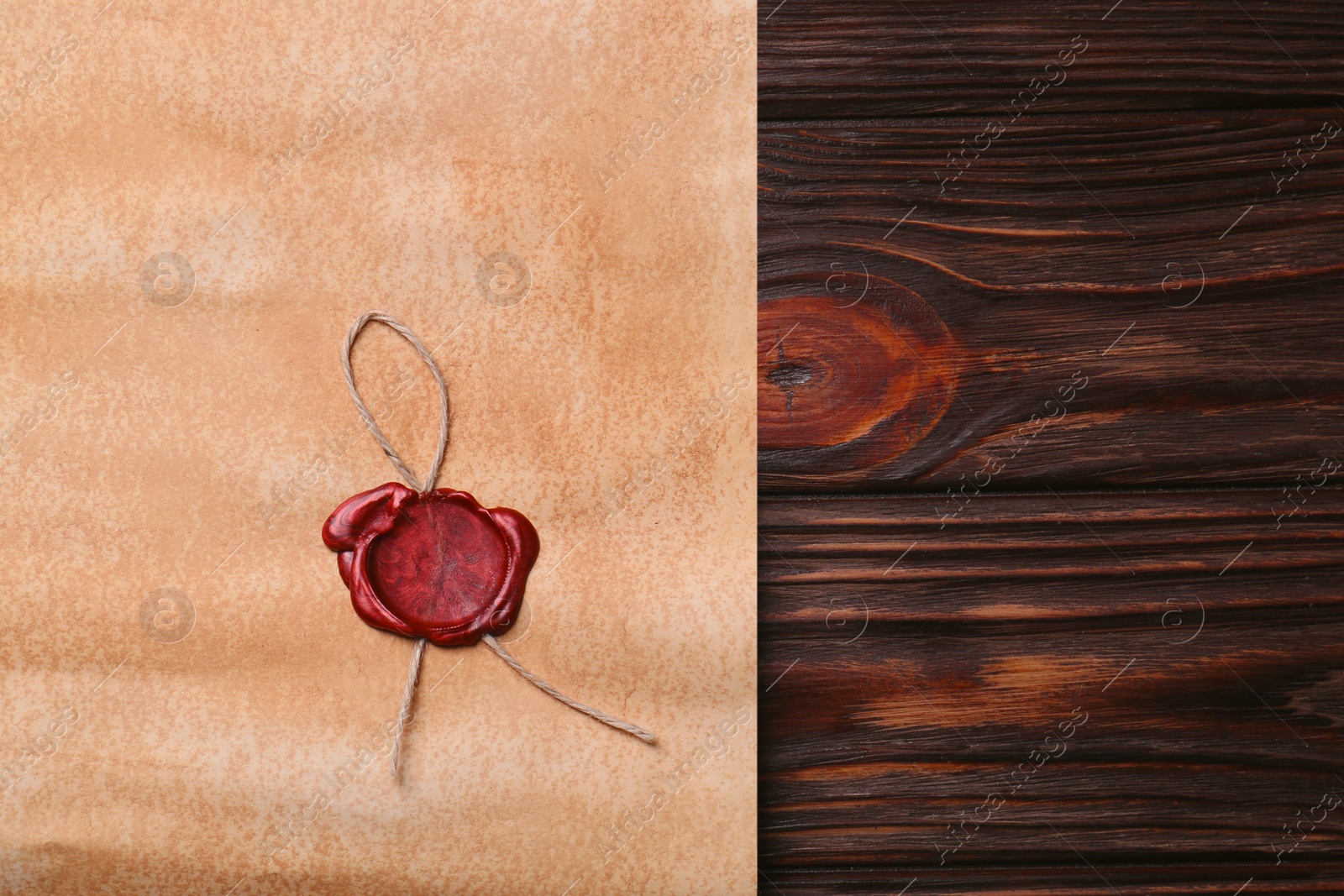 Photo of Sheet of old parchment paper with wax stamp on wooden table, top view. Space for text