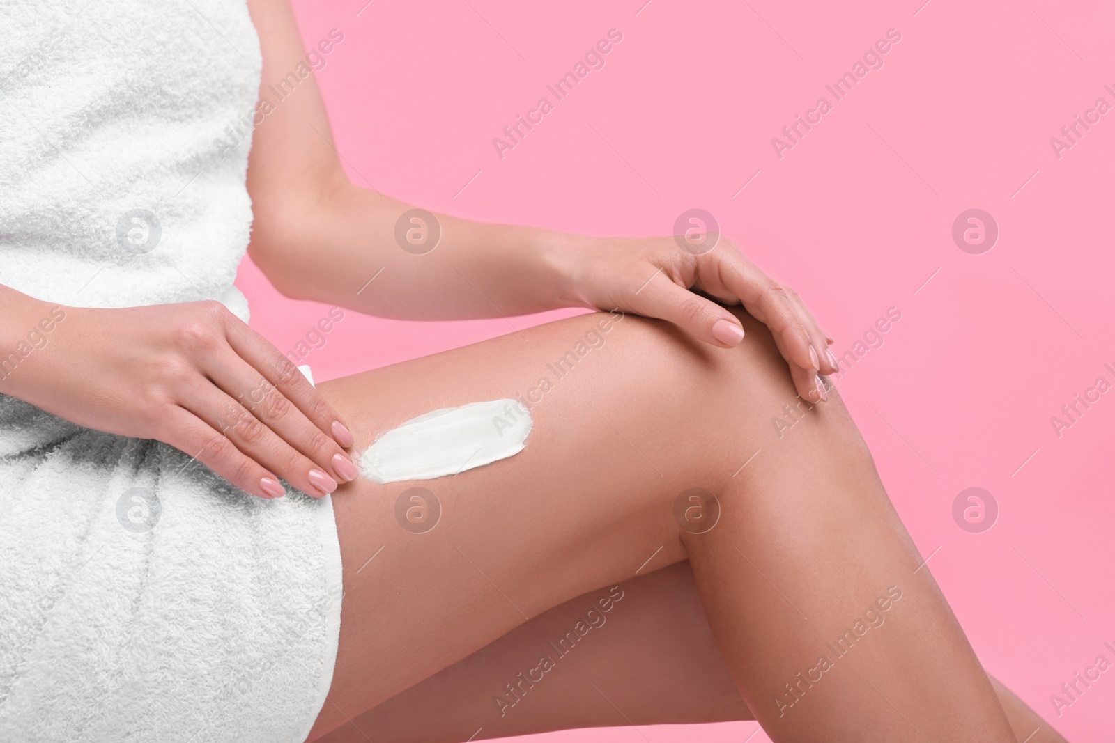 Photo of Woman with smear of body cream on her leg against pink background, closeup