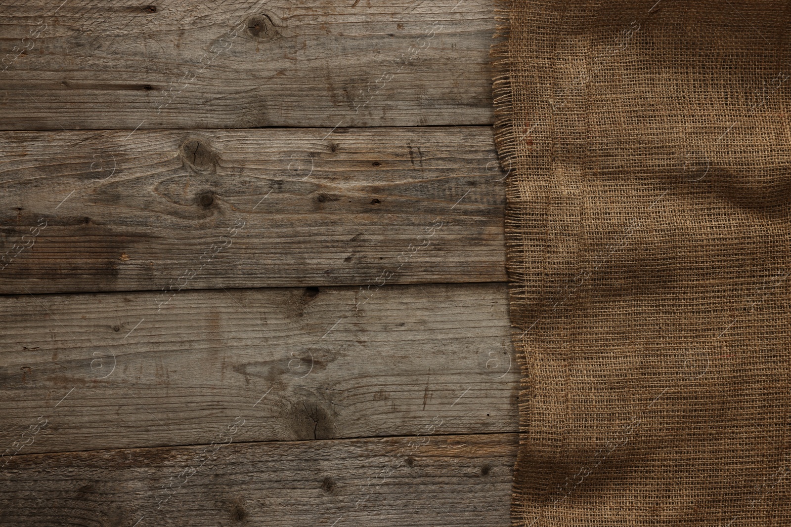 Photo of Burlap fabric on wooden table, top view. Space for text