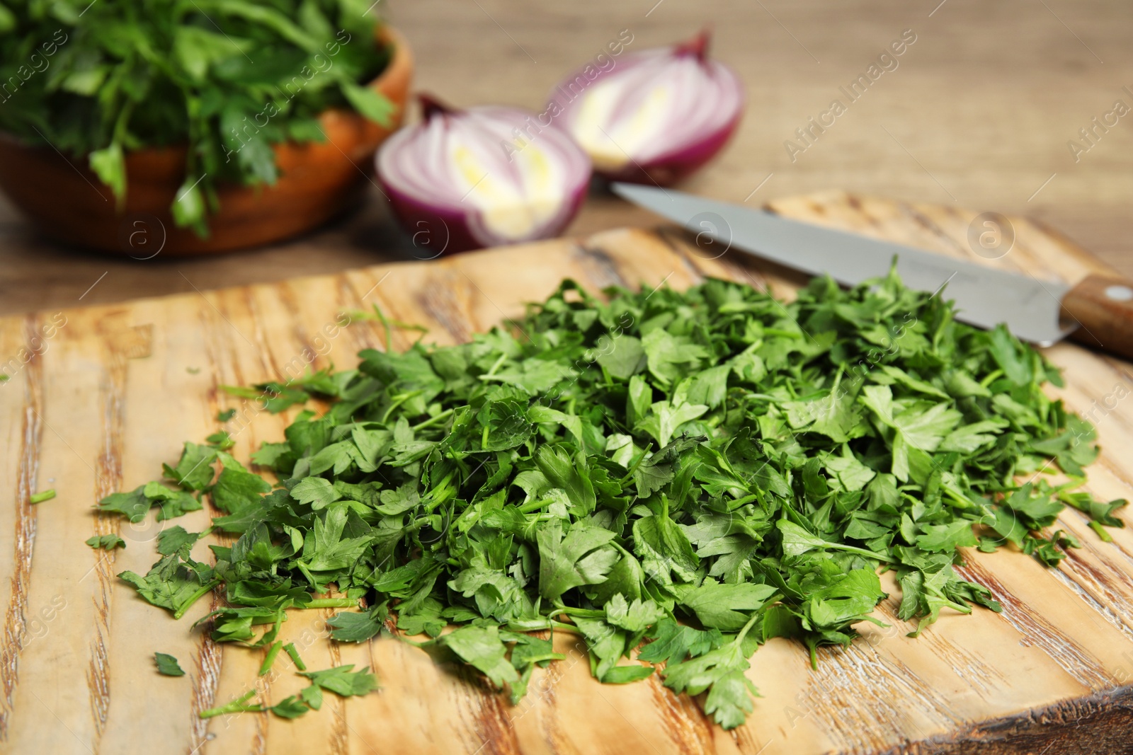 Photo of Wooden board with fresh green parsley on table, closeup