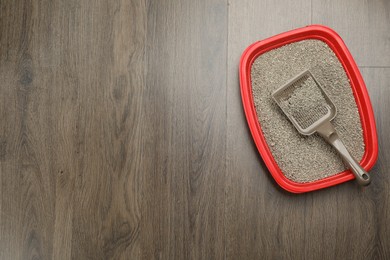 Cat litter tray with filler and scoop on wooden floor, top view. Space for text