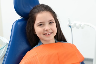 Photo of Cute little girl in chair at dentist's office
