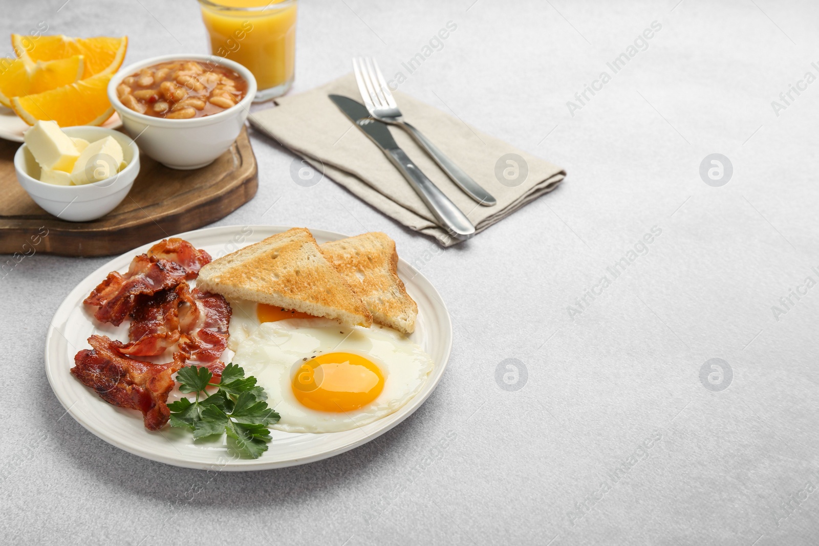 Photo of Delicious breakfast with sunny side up egg served on light table. Space for text