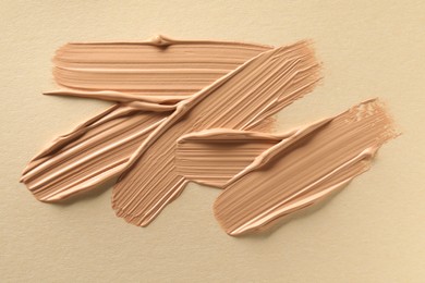 Sample of liquid skin foundation on beige background, top view