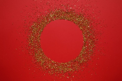 Photo of Frame of gold glitter on red background, top view. Space for text