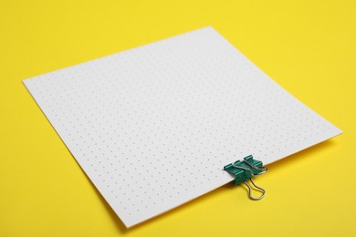 Photo of Sheet of paper with clip on yellow background