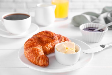 Fresh croissant and butter on white wooden table. Tasty breakfast