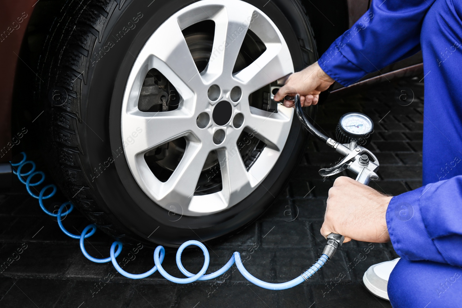 Photo of Mechanic checking tire air pressure at car service, closeup