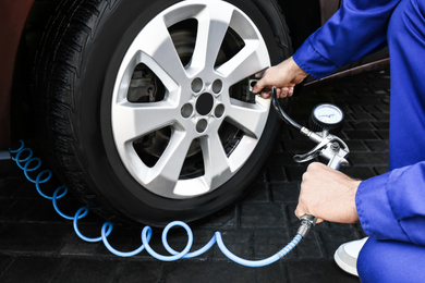 Mechanic checking tire air pressure at car service, closeup