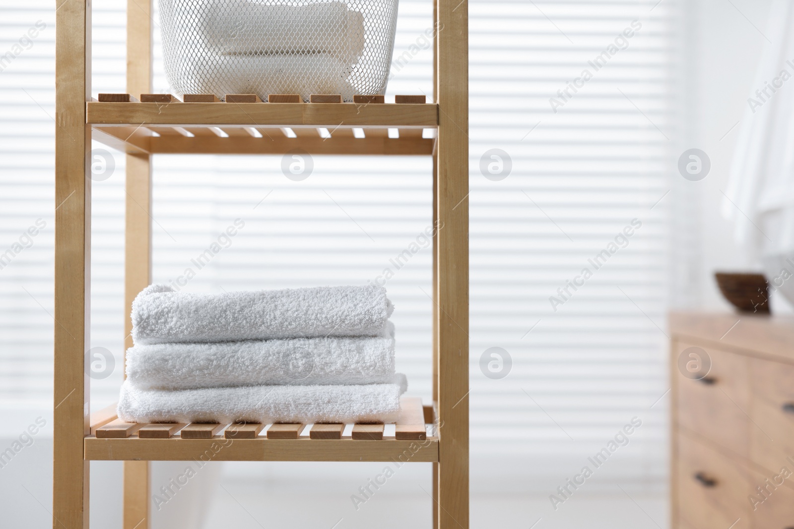 Photo of Stacked bath towel on wooden shelf indoors. Space for text