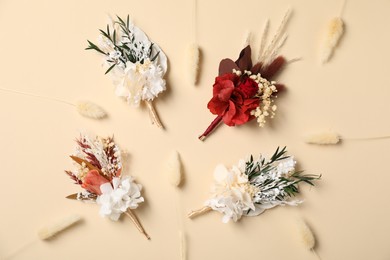 Stylish boutonnieres on beige background, flat lay