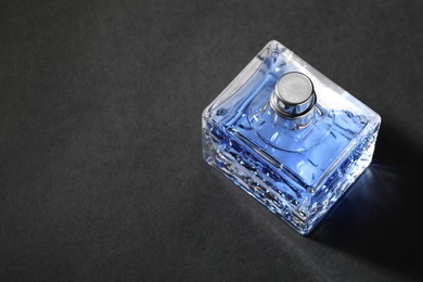 Photo of Blue men's perfume in bottle on black background, space for text