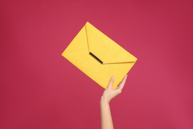 Photo of Woman holding stylish envelope bag on pink background, closeup