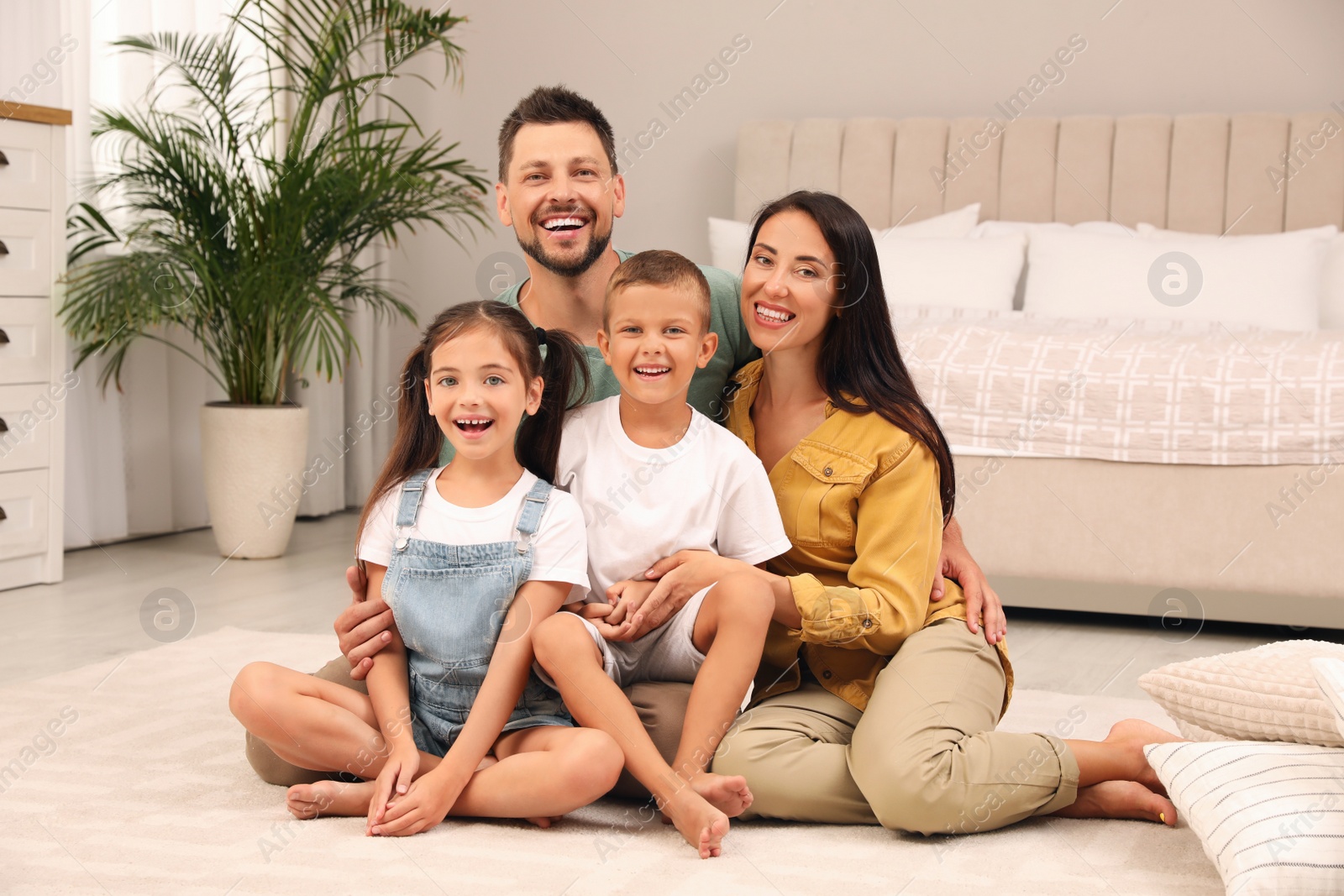 Photo of Portrait of happy family on floor in bedroom