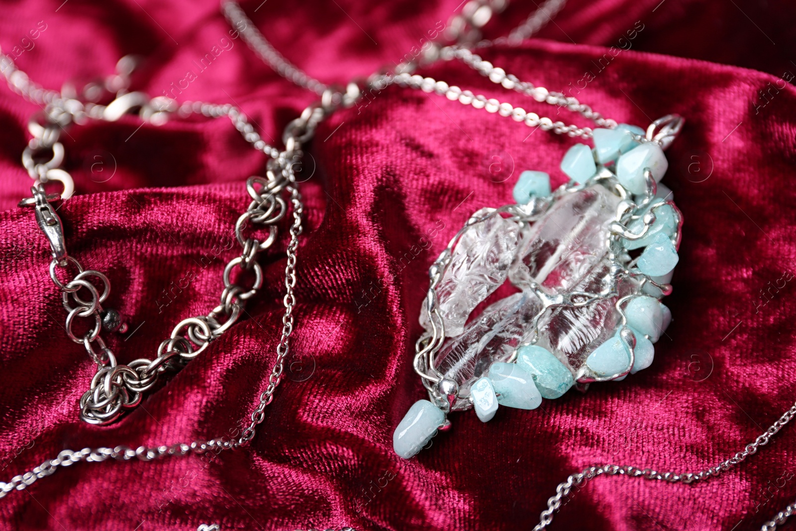 Photo of Beautiful silver necklace with pure quartz gemstones on burgundy fabric