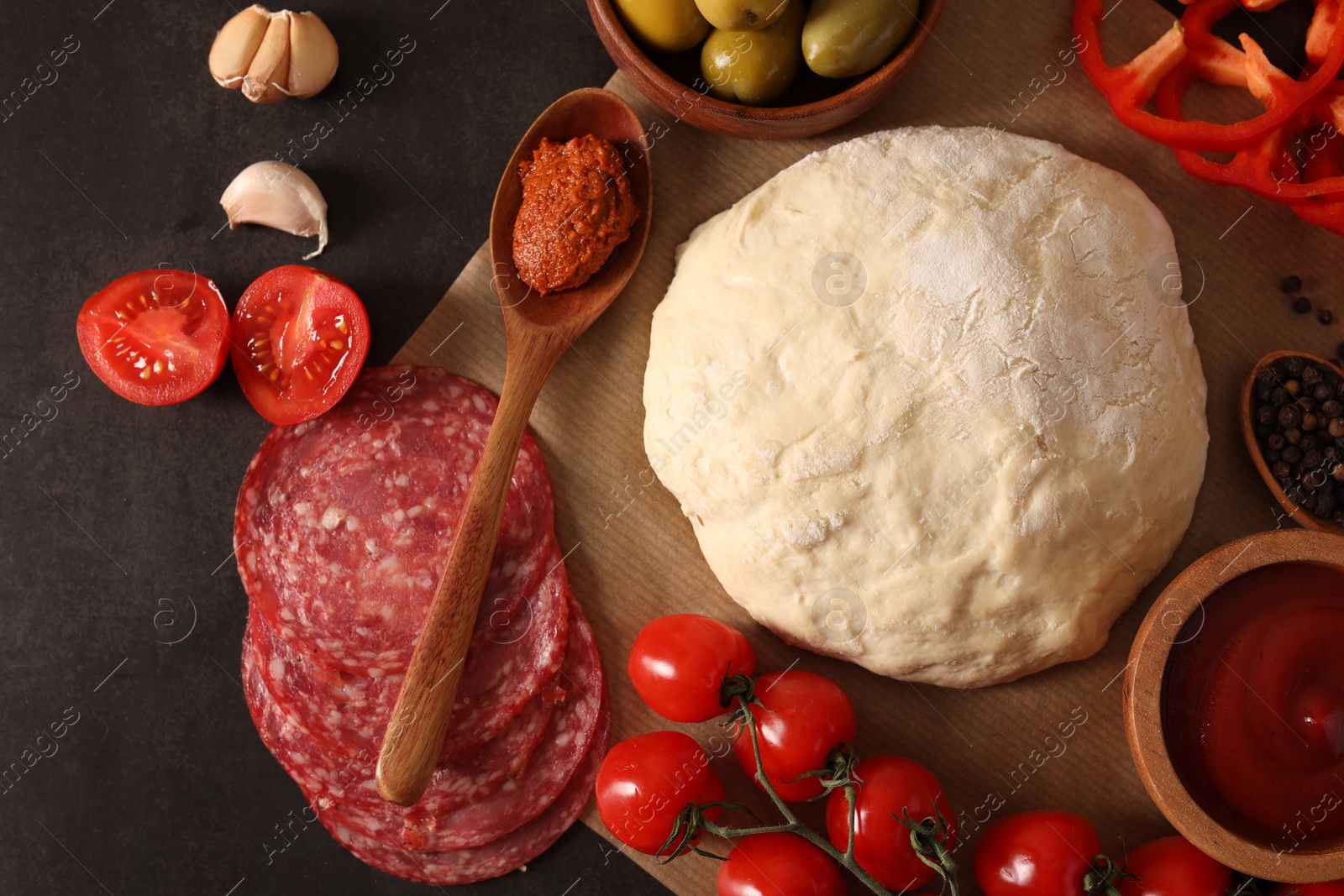 Photo of Pizza dough and products on dark table, flat lay