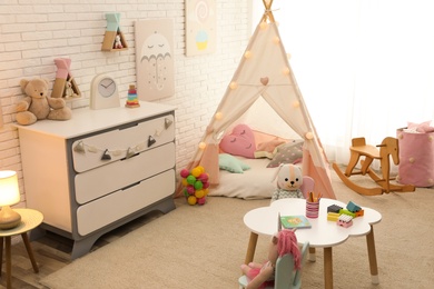 Photo of Cute child's room interior with toys and play tent