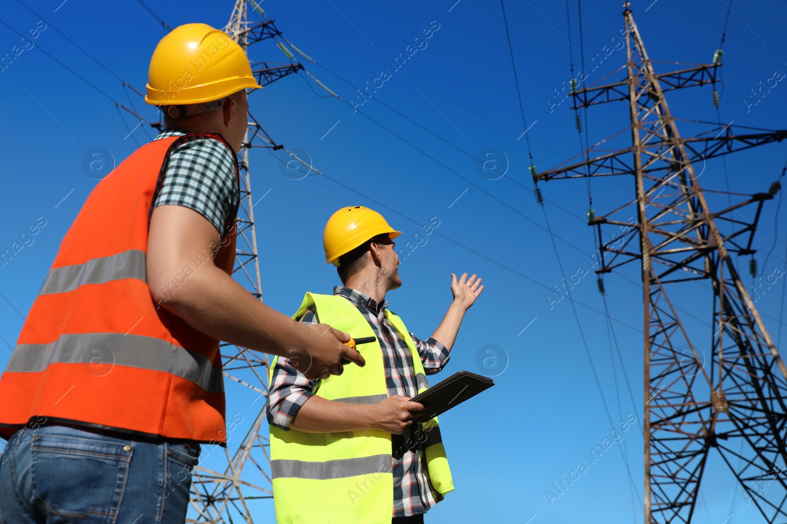 Photo of Professional electricians in uniforms near high voltage towers