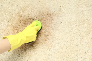 Photo of Woman removing stain from beige carpet, top view. Space for text