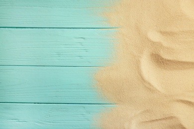 Beach sand on wooden background, top view with space for text